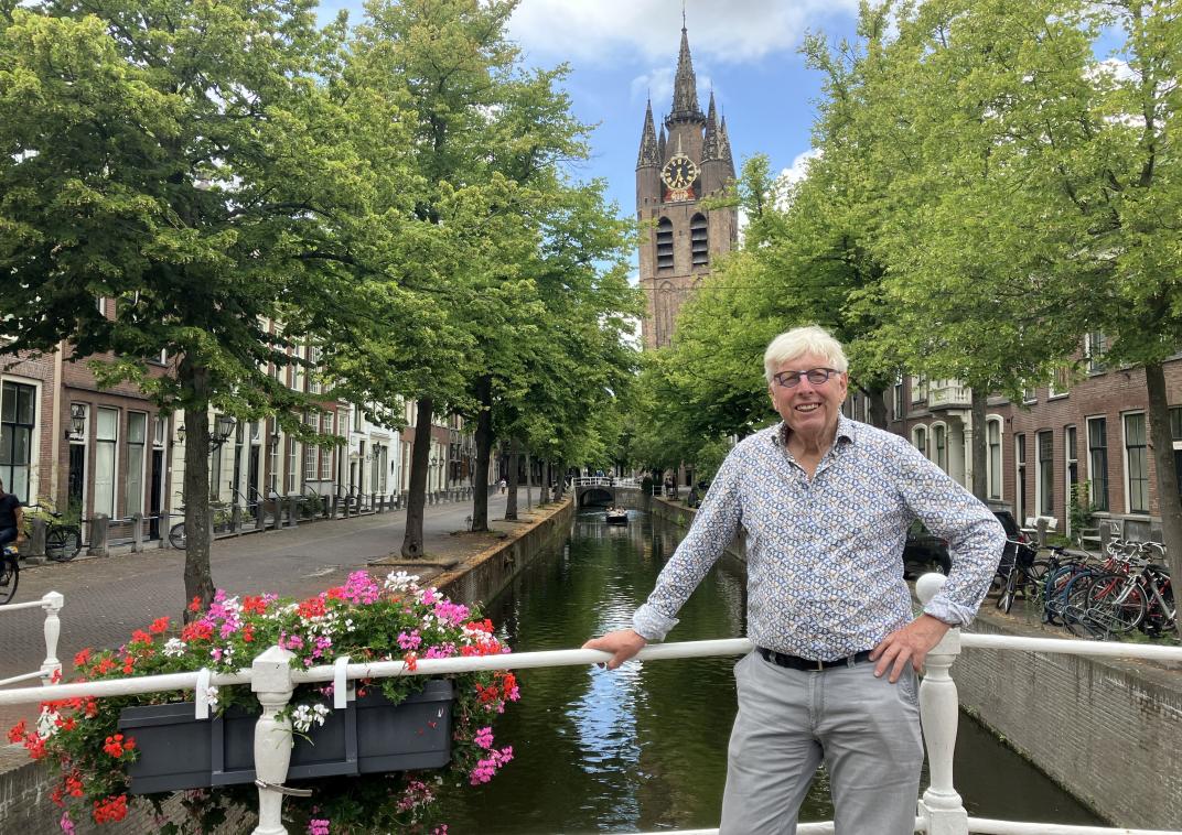 Leo Quack staat op een brug in de binnenstad, met op de achtergrond de Oude Kerk
