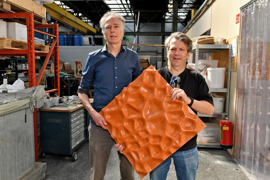Willem Bottger en Mark Lepelaar van NPSP laten een oranje gevelpaneel zien